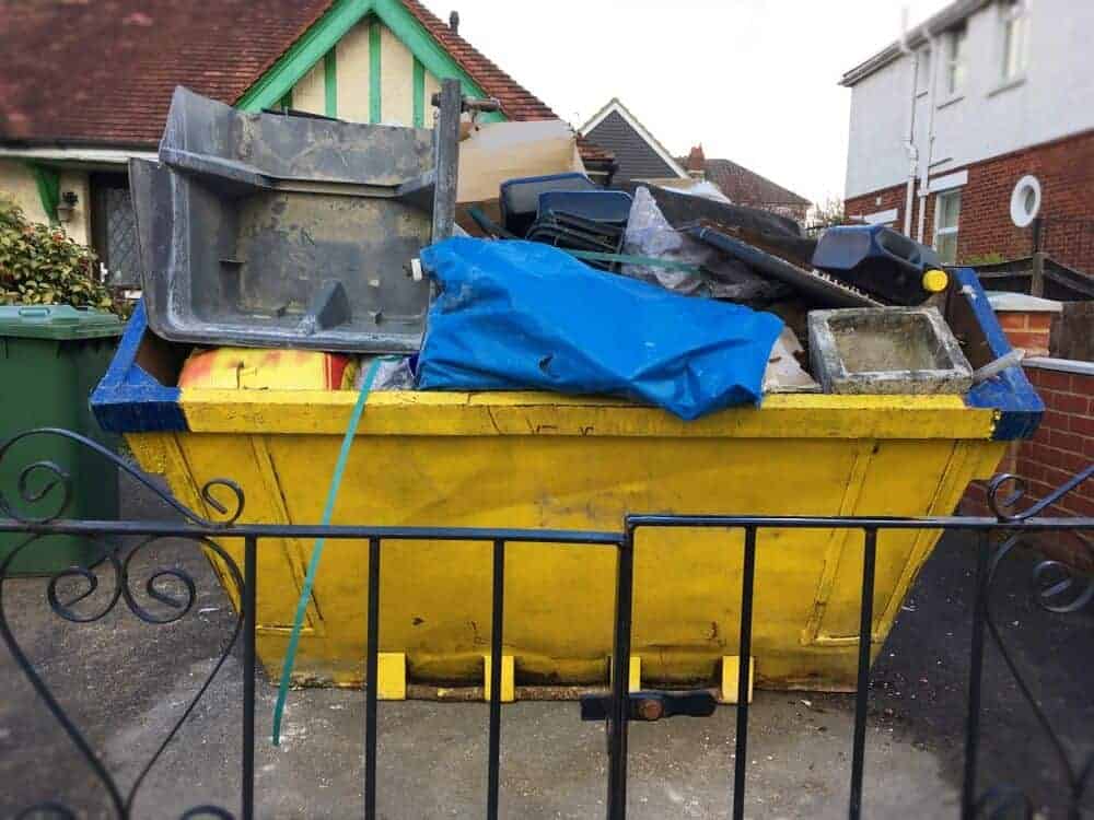 Die Reste einer Haushaltsauflösung in einem kleinen Container in der Hauseinfahrt.